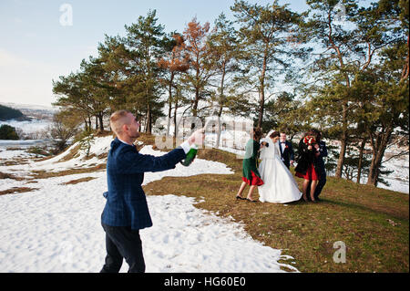 Trauzeuge mit Brautjungfern und Brautpaar trinken Champagner auf Frost-Winter-Hochzeit. Stockfoto