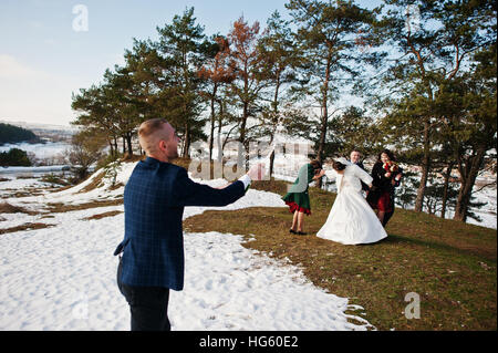 Trauzeuge mit Brautjungfern und Brautpaar trinken Champagner auf Frost-Winter-Hochzeit. Stockfoto