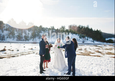 Trauzeuge mit Brautjungfern und Brautpaar trinken Champagner auf Frost-Winter-Hochzeit. Stockfoto