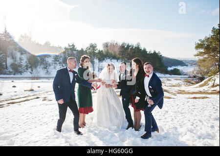 Trauzeuge mit Brautjungfern und Brautpaar trinken Champagner auf Frost-Winter-Hochzeit. Stockfoto