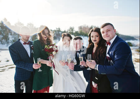 Trauzeuge mit Brautjungfern und Brautpaar trinken Champagner auf Frost-Winter-Hochzeit. Stockfoto