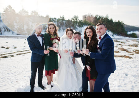Trauzeuge mit Brautjungfern und Brautpaar trinken Champagner auf Frost-Winter-Hochzeit. Stockfoto