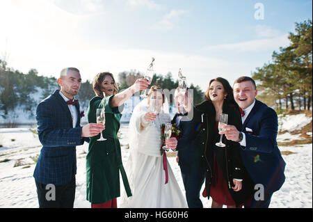 Trauzeuge mit Brautjungfern und Brautpaar trinken Champagner auf Frost-Winter-Hochzeit. Stockfoto