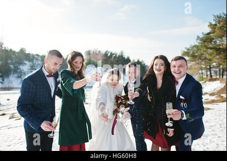 Trauzeuge mit Brautjungfern und Brautpaar trinken Champagner auf Frost-Winter-Hochzeit. Stockfoto