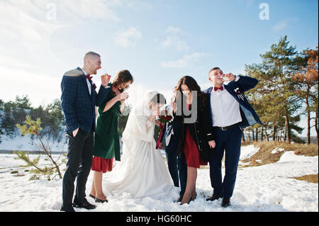 Trauzeuge mit Brautjungfern und Brautpaar trinken Champagner auf Frost-Winter-Hochzeit. Stockfoto