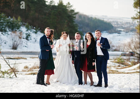Trauzeuge mit Brautjungfern und Brautpaar trinken Champagner auf Frost-Winter-Hochzeit. Stockfoto