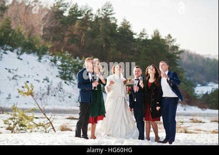 Trauzeuge mit Brautjungfern und Brautpaar trinken Champagner auf Frost-Winter-Hochzeit. Stockfoto