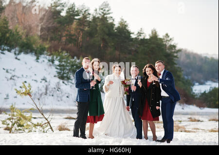 Trauzeuge mit Brautjungfern und Brautpaar trinken Champagner auf Frost-Winter-Hochzeit. Stockfoto