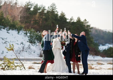 Trauzeuge mit Brautjungfern und Brautpaar trinken Champagner auf Frost-Winter-Hochzeit. Stockfoto