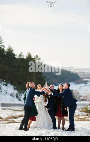 Trauzeuge mit Brautjungfern und Brautpaar auf Frost Winter Hochzeit Champagner trinken und blickte auf Drohne Videoaufzeichnung. Stockfoto