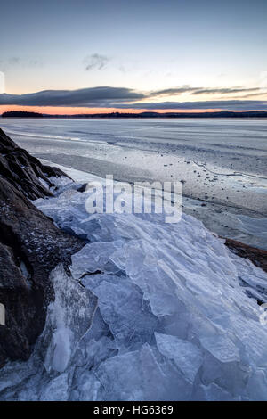 Haufen von kleinen gestoßenem Eis von einem Felsen auf einem zugefrorenen See in Finnland im Winter. Stockfoto