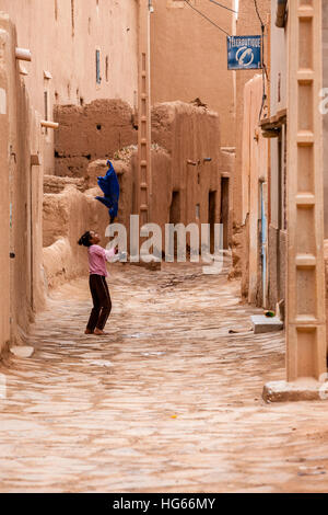 Elkhorbat, Marokko.  Straßenszene in der Kasbah, junges Mädchen mit Besen. Stockfoto