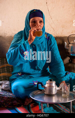 Ksar Elkhorbat, Marokko.  Mittleren Alters Amazigh Berber Frau trinken Tee in ihrem Wohnzimmer. Stockfoto