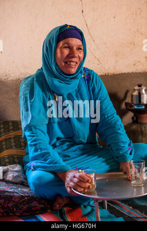 Ksar Elkhorbat, Marokko.  Mittleren Alters Amazigh Berber Frau trinken Tee in ihrem Wohnzimmer. Stockfoto