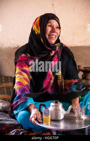 Ksar Elkhorbat, Marokko.  Mittleren Alters Amazigh Berber Frau trinken Tee in ihrem Wohnzimmer. Stockfoto