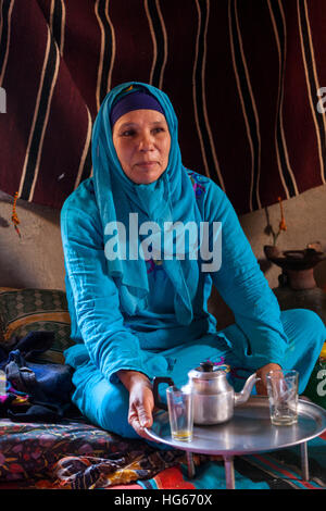 Ksar Elkhorbat, Marokko.  Mittleren Alters Amazigh Berber Frau trinken Tee in ihrem Wohnzimmer. Stockfoto