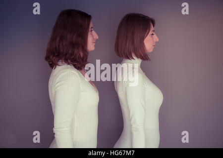 Doppelgänger / Alter Ego unter dem Motto Fotoshooting: zwei junge Frauen Mädchen tragen passende Kleidung Stand stehend zusammen passende Echo Spiegelung jedes andere körperliche Haltung und Ausdruck - stehend im Profil seitlich auf, Blick in die Zukunft Stockfoto