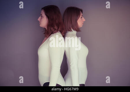 Doppelgänger / Alter Ego unter dem Motto Fotoshooting: zwei junge Frauen Mädchen tragen passende Kleidung Stand zusammenstehen passende Echo Spiegelung jedes andere körperliche Haltung und Ausdruck - Stand zurück um zu zurück blicken nicht auf einander Stockfoto