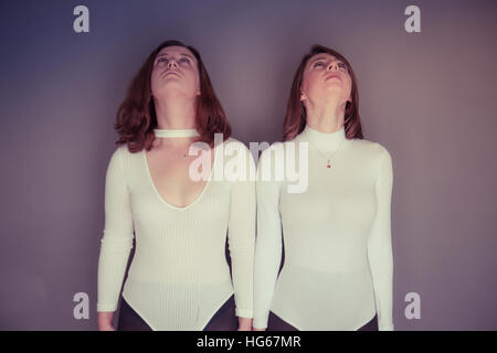 Doppelgänger / Alter Ego unter dem Motto Fotoshooting: zwei junge Frauen, Mädchen tragen passende Kleidung Stand stehend zusammen passende Echo Spiegelung jeweils anderen physischen darstellen, und Ausdruck - auf der Suche nach oben Stockfoto