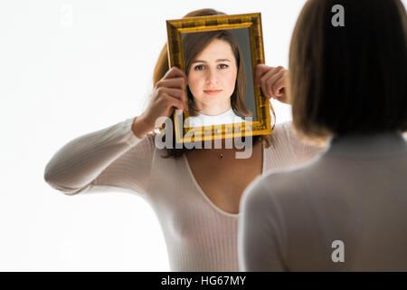 Doppelgänger / Alter Ego unter dem Motto Fotoshooting: eine junge Frau-Mädchen ihre Reflexion in einem Spiegel betrachten statt mein ein "Zwilling" tragen die gleiche Kleidung Stockfoto