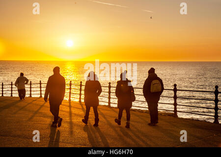 Strandpromenade, Sonnenuntergang, Menschen, Schatten, Wandern, Silhouette, Sonne, Himmel, Person, Wasser, Lifestyle, Licht, Sonnenlicht, gemeinsam, Naturspaziergang bei Sonnenuntergang Blackpool, Lancashire, Großbritannien. Januar 2017. Wetter in Großbritannien. Lange Schatten, während die Menschen an einem bitterkalten Wintertag entlang der Promenade spazieren und die letzte Sonne genießen. Stockfoto