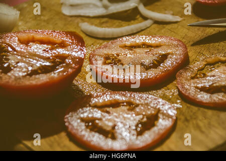 Foto von einem Messer, Tomatenscheiben und Zwiebeln auf ein Holz Schneidebrett Stockfoto