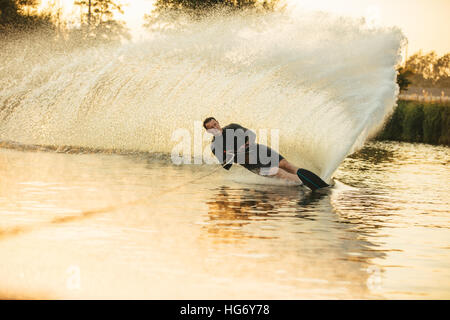 Mann Wakeboarden an einem See mit Spritzer Wasser. Wakeboarder Surfen über den See Angeberei ist Fertigkeit. Stockfoto