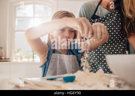 Wunderschönes kleines Mädchen lernt, eine Mahlzeit in der Küche zu kochen. Mädchen, das einen Teig zum Backen mit ihrer Mutter stand. Stockfoto