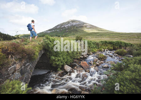 Einsamer Wanderer Stand auf einer alten Brücke in der vergifteten Glen mit Blick auf Mount Errigal. Glenveagh Nationalpark, County Donegal, ich Stockfoto