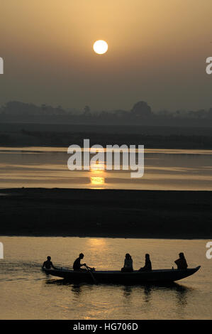 Silhouette des Menschen in einem Boot bei Sonnenaufgang über dem Ganges in Varanasi, Indien Stockfoto