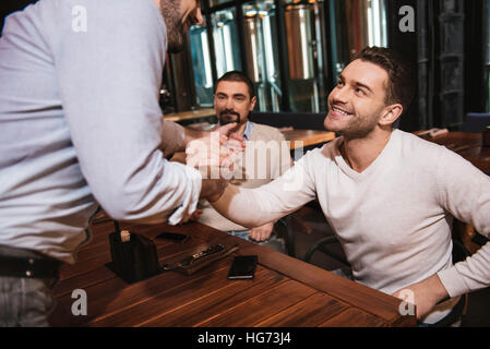 Fröhliche Mann Händeschütteln mit seinem Freund Stockfoto