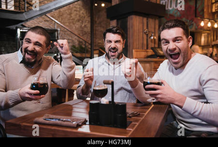 Fröhlich jubelnden Freunde beobachten eines Fußballspiels Stockfoto