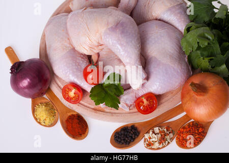 frische Hähnchenschenkel und Drumsticks auf einem Holzbrett mit Gemüse Stockfoto