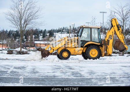 Baggerlader Schneeräumung von einem Parkplatz. Stockfoto