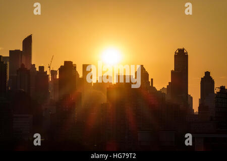 New York City, NY NYC, Queens, Long Island City, Aussicht, Skyline von Manhattan, Gebäude, Sonnenuntergang, Sonnenstrahlen, Orange, Gelb, Silhouette, Besucher reisen Reise Tour t Stockfoto