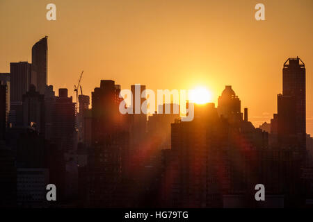 New York City, NY NYC, Queens, Long Island City, Aussicht, Skyline von Manhattan, Gebäude, Sonnenuntergang, Sonnenstrahlen, Orange, Gelb, Silhouette, Besucher reisen Reise Tour t Stockfoto