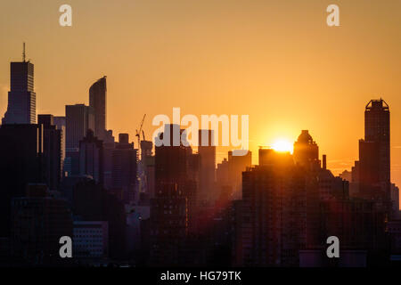 New York City, NY NYC, Queens, Long Island City, Aussicht, Skyline von Manhattan, Gebäude, Sonnenuntergang, Sonnenstrahlen, Orange, Gelb, Silhouette, Besucher reisen Reise Tour t Stockfoto