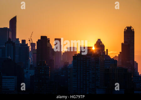 New York City, NY NYC, Queens, Long Island City, Aussicht, Skyline von Manhattan, Gebäude, Sonnenuntergang, Sonnenstrahlen, Orange, Gelb, Silhouette, Besucher reisen Reise Tour t Stockfoto