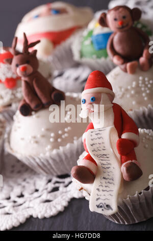 Schöne Weihnachts Cupcakes dekoriert mit der Figur des Santa-Makro auf dem Tisch. vertikale Stockfoto