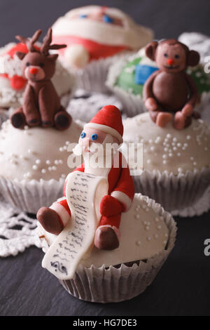 Weihnachts-Muffins verziert mit der Figur des Santa-close-up auf dem Tisch. vertikale Stockfoto