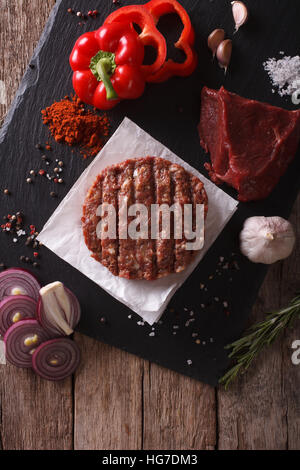 Rohe Burger Schnitzel mit den Zutaten auf den Tisch. vertikale Ansicht von oben Stockfoto