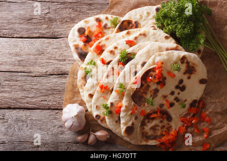 Indische Naan Fladenbrot mit Knoblauch und Kräutern auf dem Tisch. horizontale Ansicht von oben Stockfoto