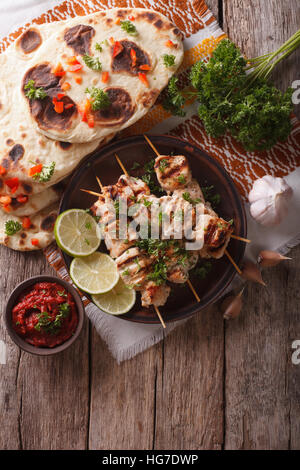 Chicken Tikka auf Spieße, Naan Fladenbrot und Chutney. vertikale Ansicht von oben Stockfoto