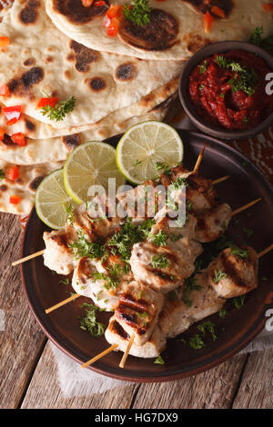 Chicken Tikka-Spieße und Naan Fladenbrot mit Chutney Soße Nahaufnahme auf dem Tisch. vertikale Stockfoto