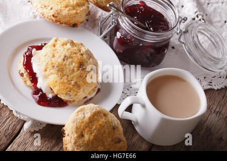 Hausgemachte Scones mit Marmelade und Tee mit Milch Nahaufnahme auf dem Tisch. horizontale Stockfoto