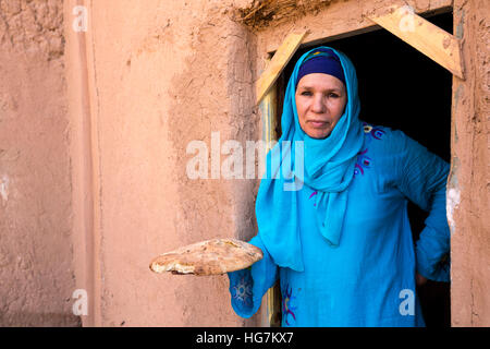 Ksar Elkhorbat, Marokko.  Amazigh Berber Frau in ihrer Tür halten frisch gebackenes Brot. Stockfoto