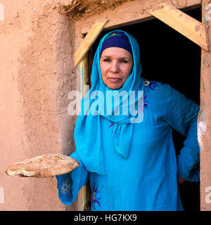 Ksar Elkhorbat, Marokko.  Amazigh Berber Frau in ihrer Tür halten frisch gebackenes Brot. Stockfoto