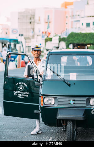 Ein älterer Mann trägt einen Seemann-uniform neben eine dreirädrige "Ape" Fahrzeug auf der Insel Ponza, Italien Stockfoto