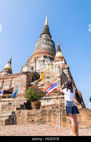 Tourist-Teenager-Mädchen stehen nehmen Sie ein Foto des Buddha Statue und alte Pagode auf blauen Himmelshintergrund am Wat Yai Chaimongkol-Tempel Stockfoto