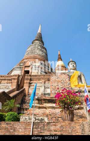 Buddha-Statue am unteren Rand eine große alte Pagode auf blauen Himmelshintergrund am Wat Yai Chai Mongkon Tempel in Phra Nakhon Si Ayutthaya Historical Stockfoto